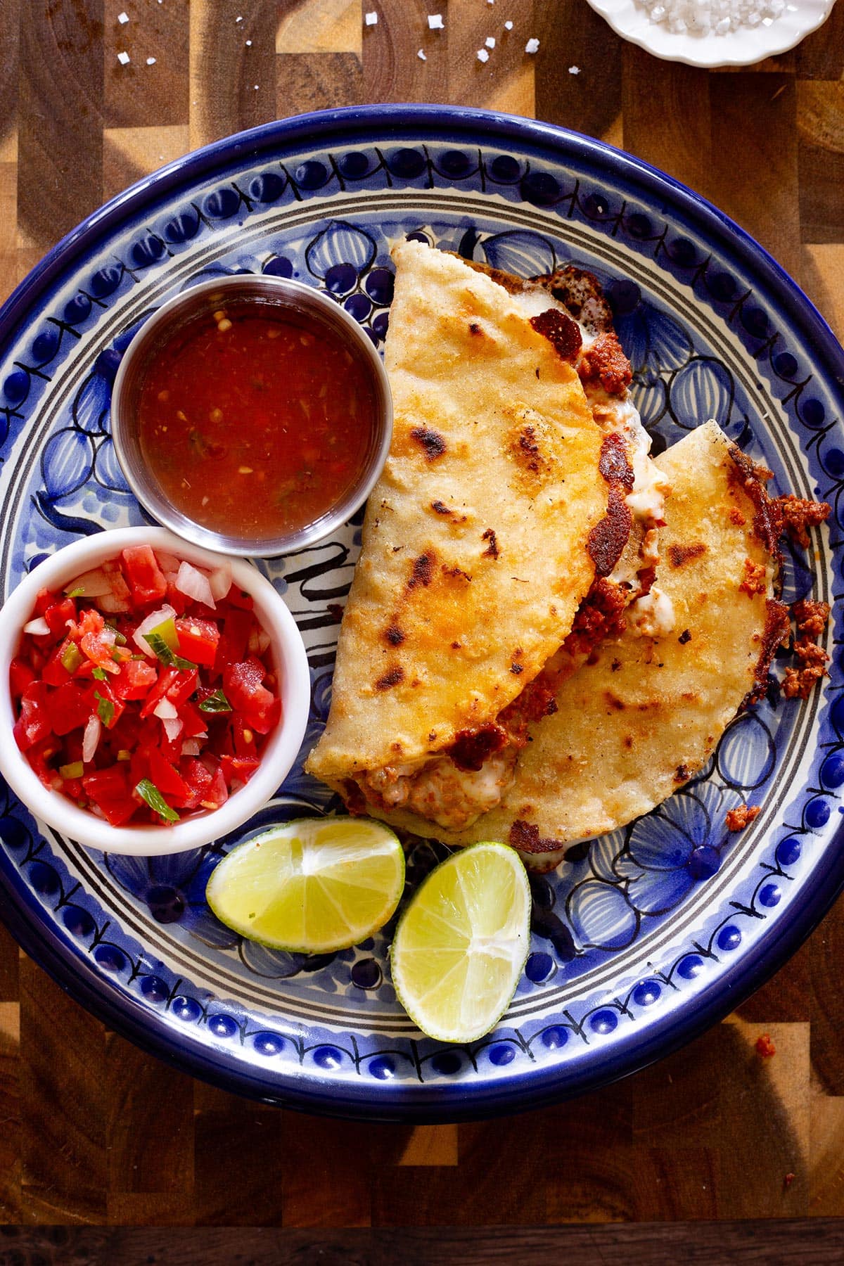 Quesadillas de Chorizo on a plate with a small bowl of salsa and a bowl of pico de gallo.