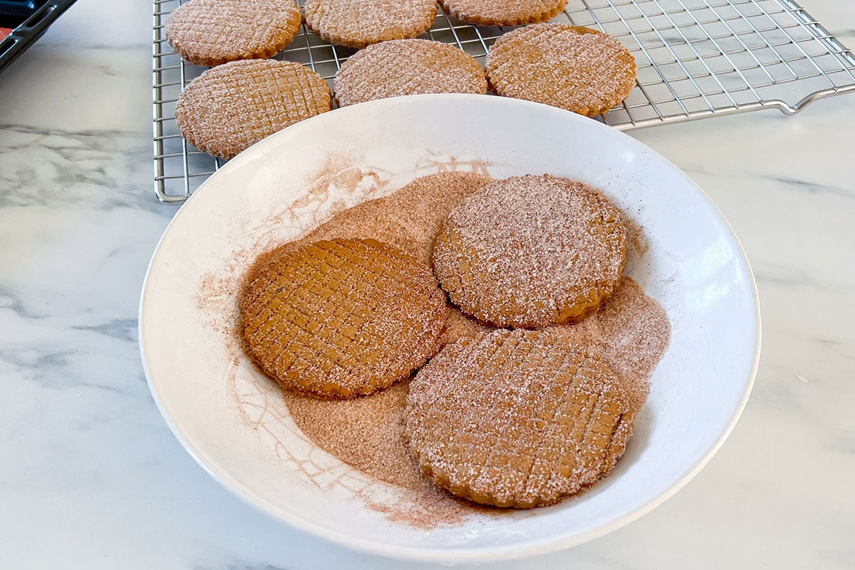 Freshly baked Galletas de Canela or Canelitas on a plate with sugar and cinnamon.