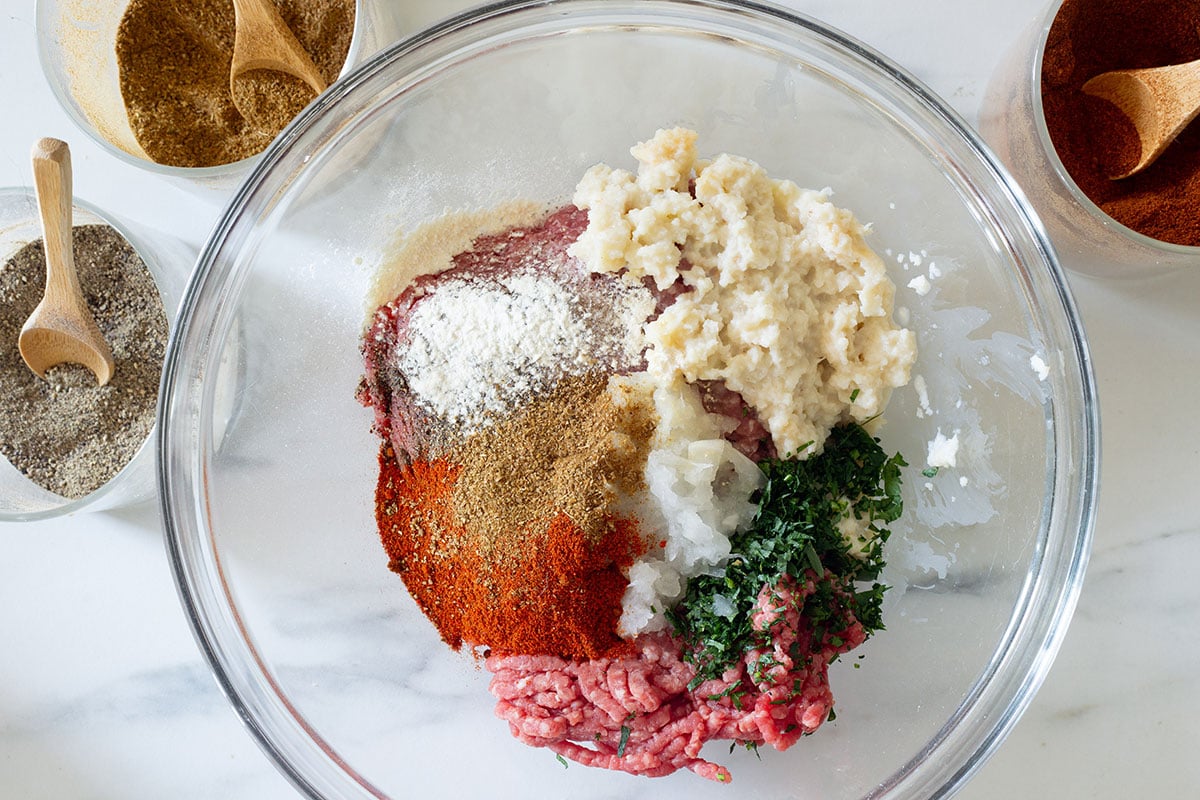 Finely ground meat with soaked bread, spices, and seasonings in a bowl for Mexican pacholas.