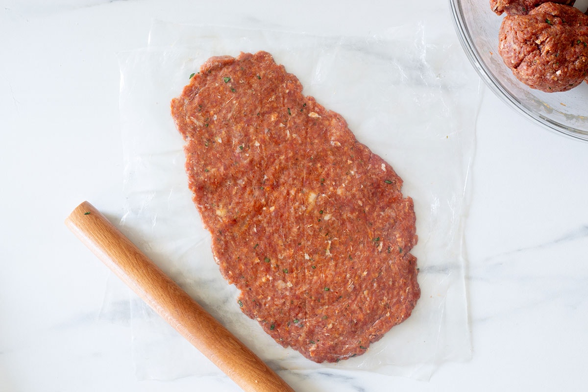 Shaped Mexican pachola between two sheets of plastic with a rolling pin.